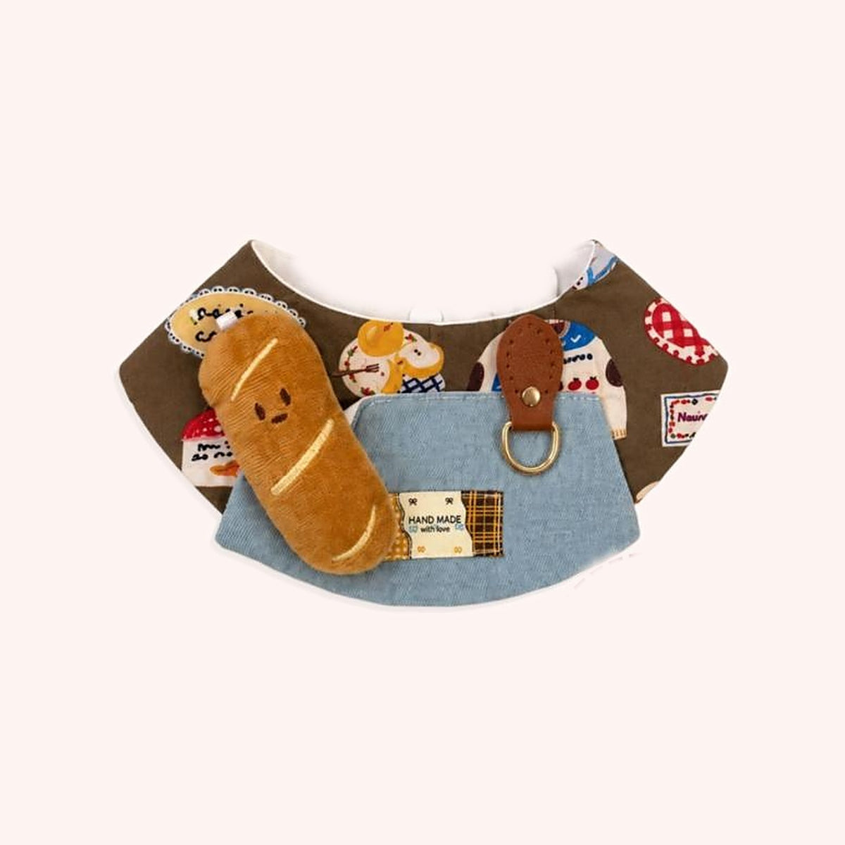 Product photo: Little Baguette Pet Bib — Brown bakery-print bib with a denim apron pocket and a plush baguette.