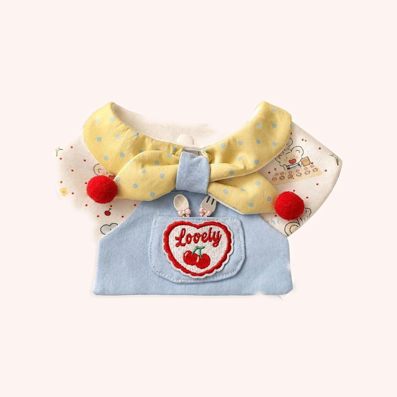 Product photo: Cherry Chef Pet Bib — Polka-dot collar and bow over a denim apron with a cherry “Lovely” patch and red pom-poms.
