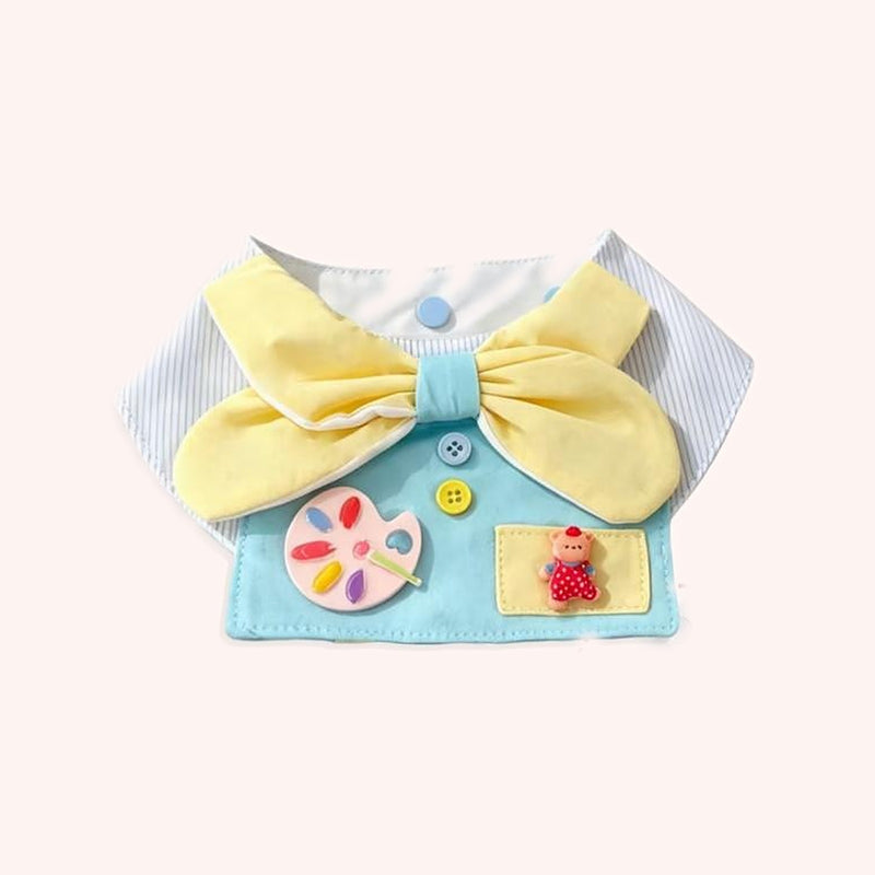 Product photo: Little Painter Pet Bib — Sky-blue smock with a big lemon bow, a painter's palette and a little bear in the pocket.