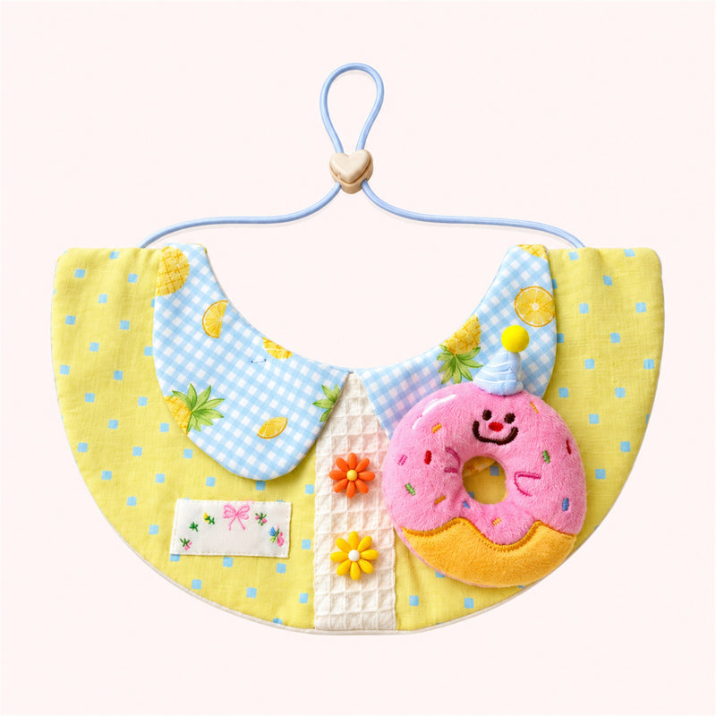 AI-cleaned product photo: Pineapple Bun Pet Bib — Lemon polka-dot bib with a gingham fruit collar and a pink party-donut plush.