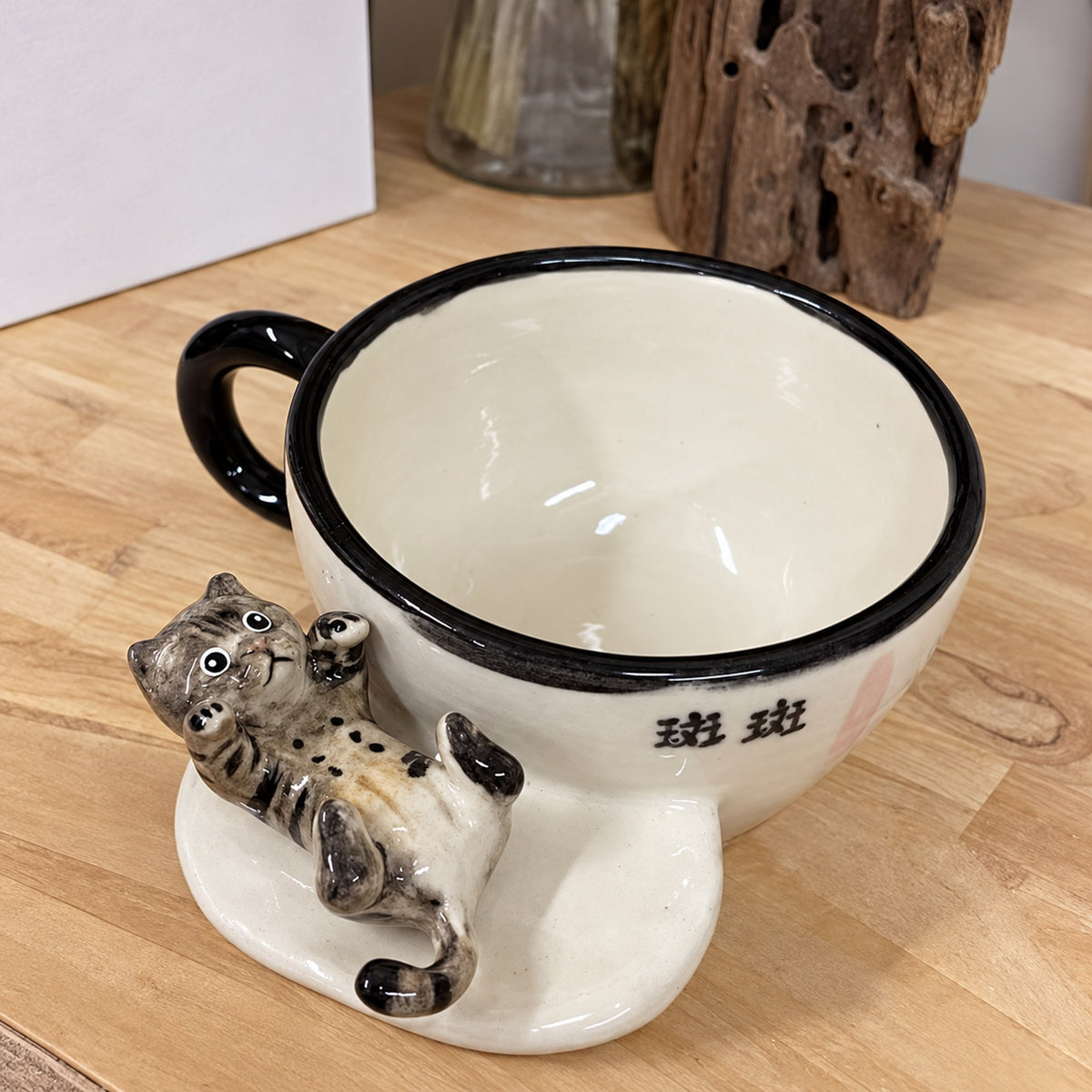 AI-cleaned product photo: Lying outside pose, sculpted tabby lying against the mug