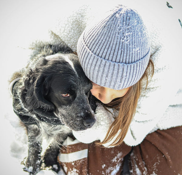 Woman hugging her dog in the snow