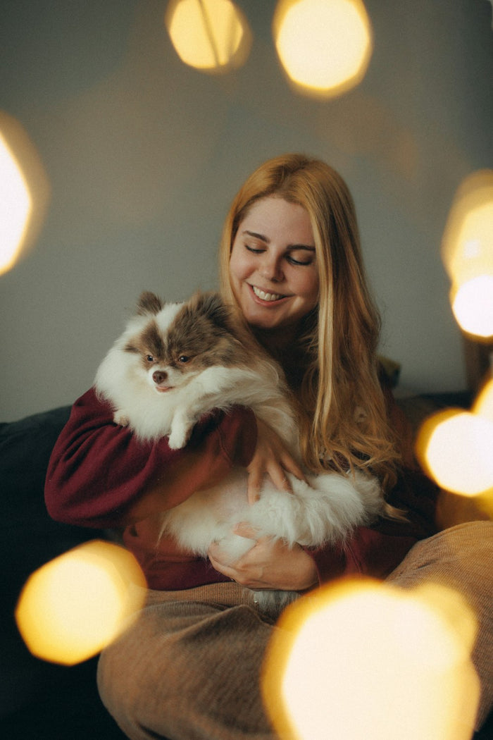 Smiling woman holding her fluffy dog indoors